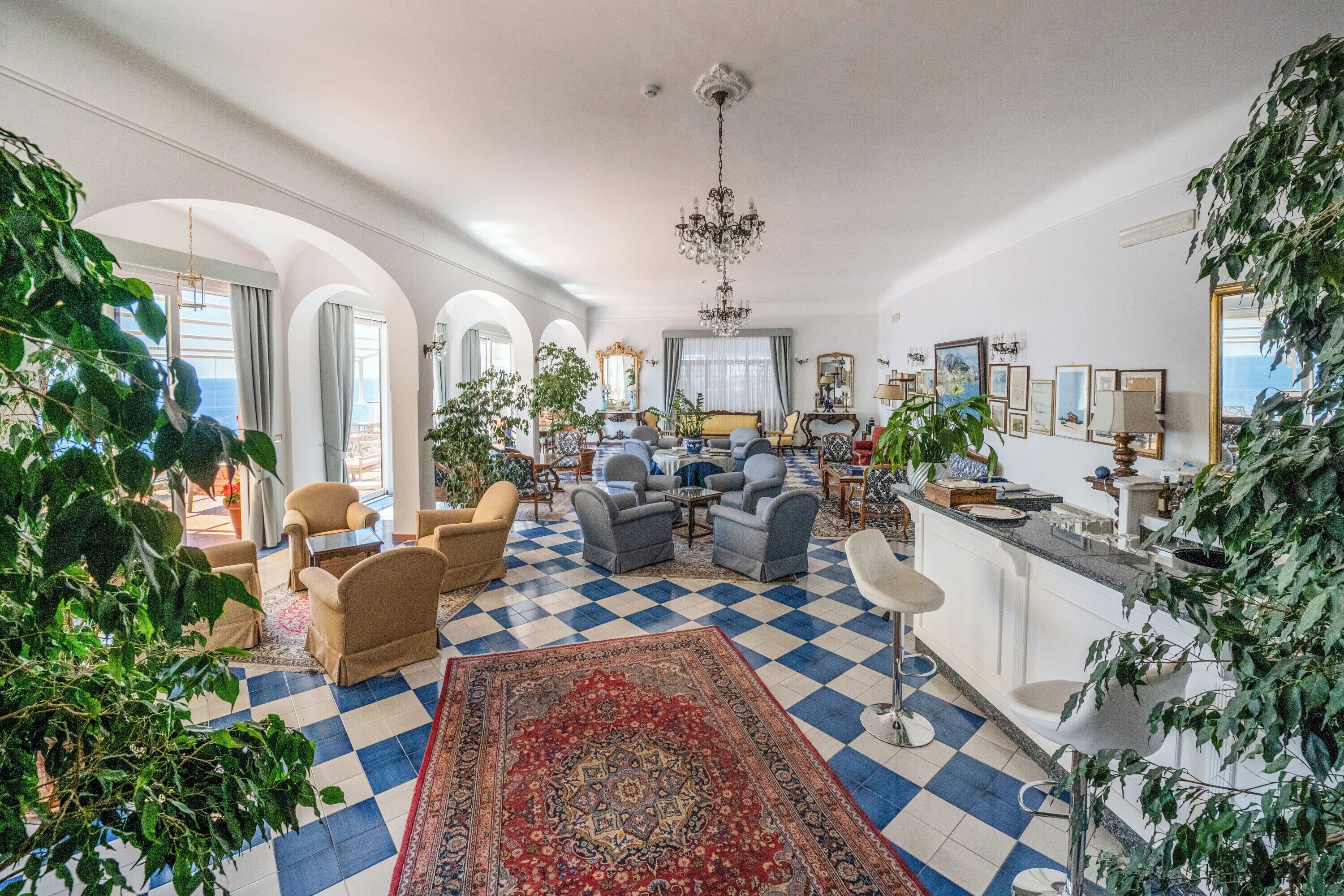 A spacious living room with a checkered floor, a large rug, and multiple seating areas.