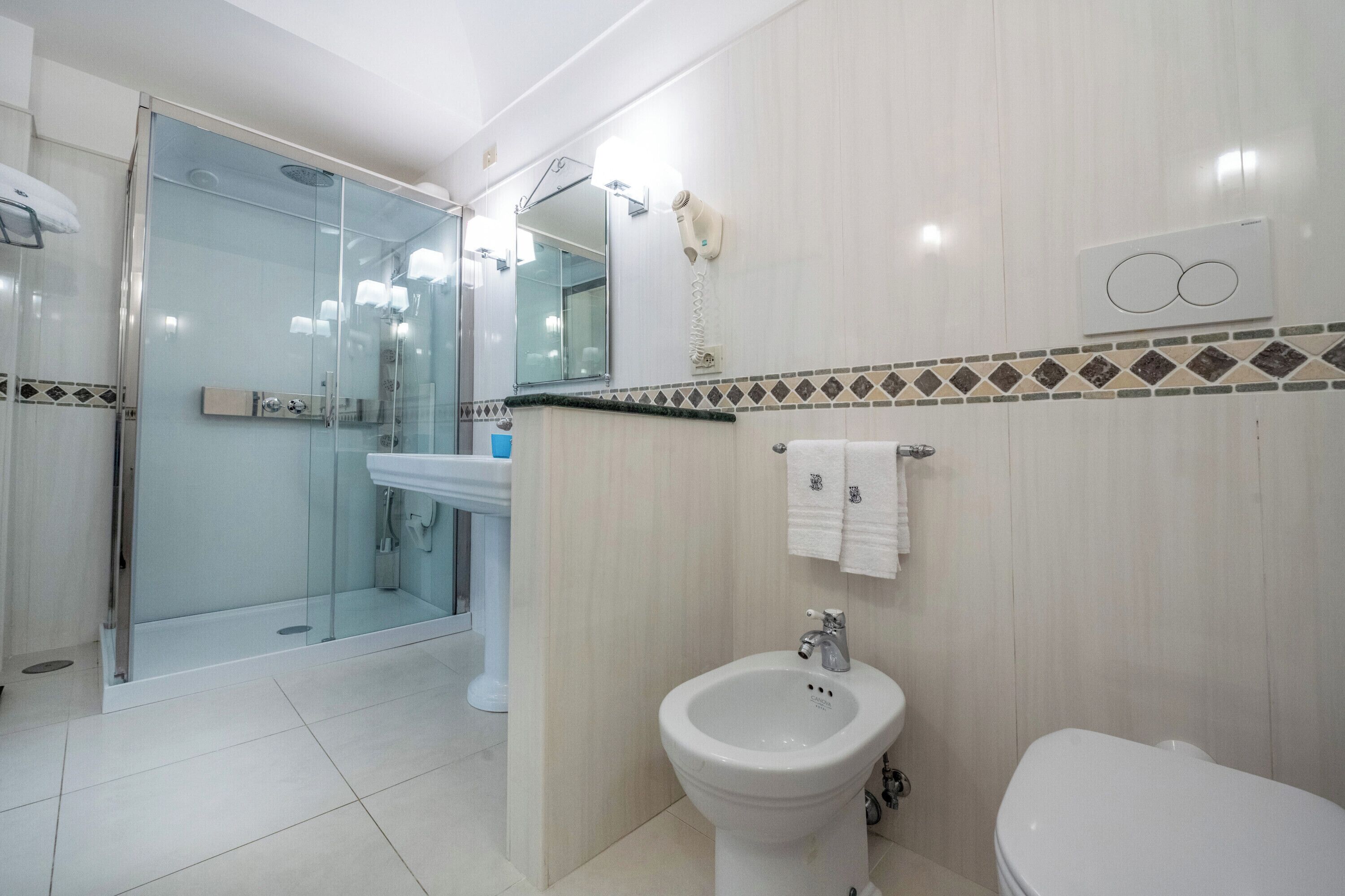 Une salle de bain moderne avec une douche à parois de verre, un lavabo sur colonne et des toilettes.