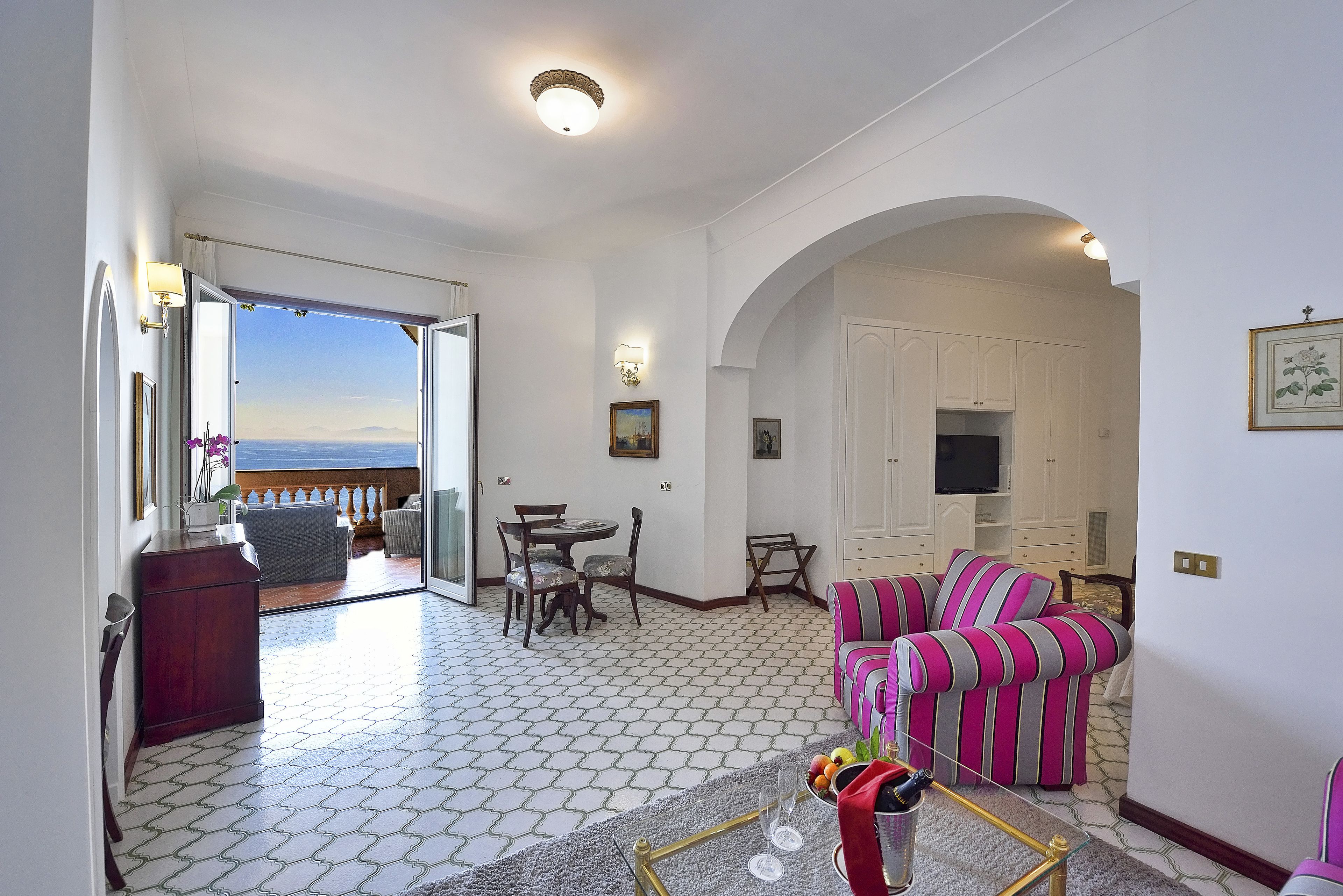 A living room with a view of the sea, a dining area, and a striped sofa.