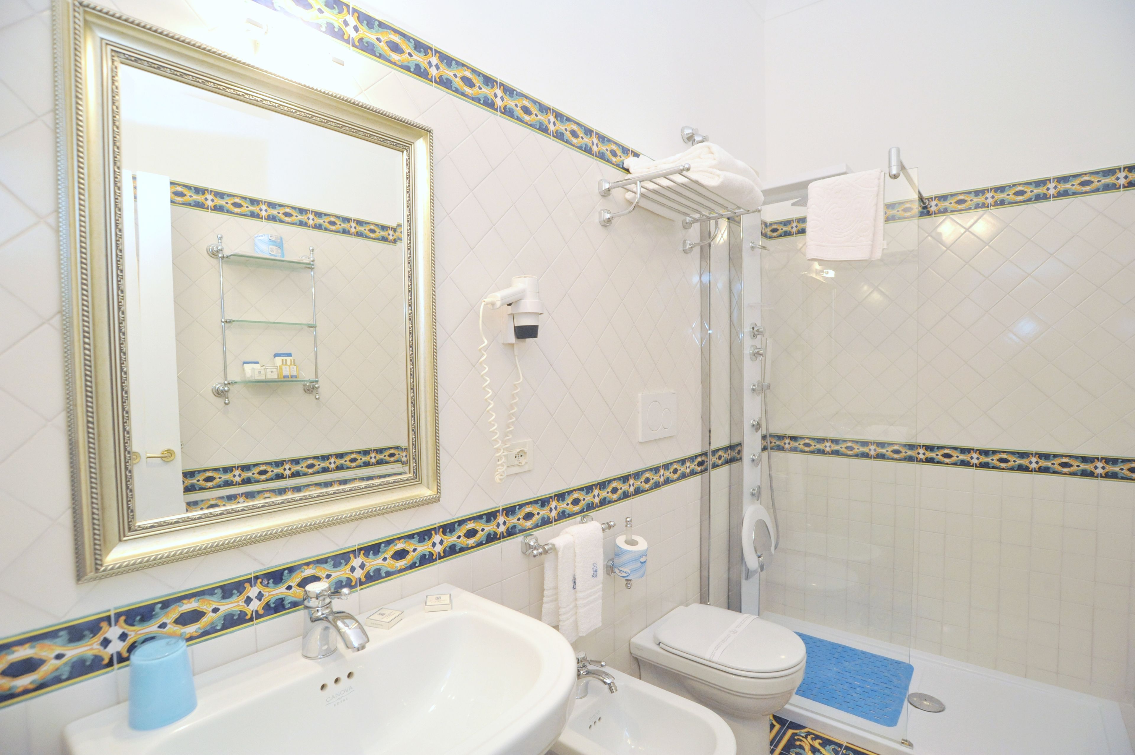 Ein Badezimmer mit großem Spiegel, Waschbecken, Toilette und Duschbereich.