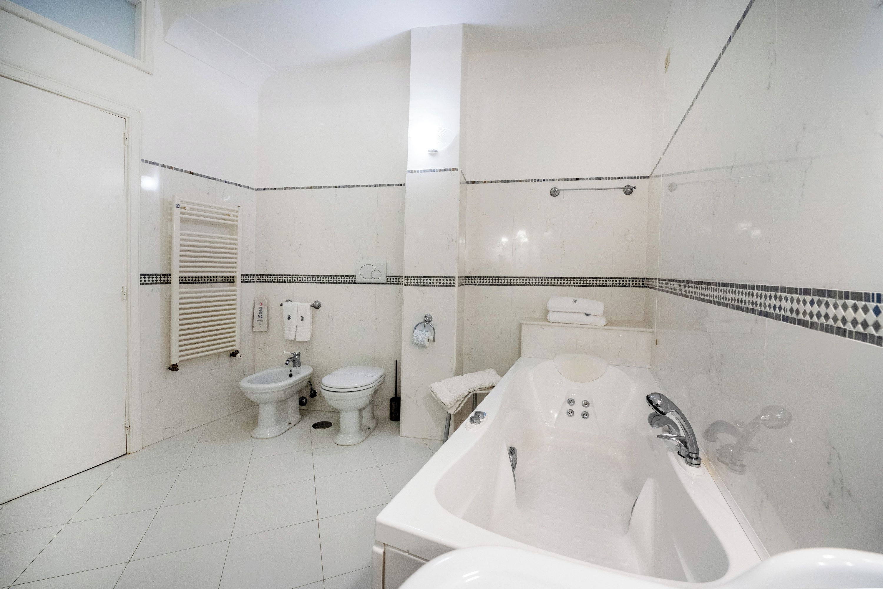 Een badkamer met een bad, toilet en bidet.