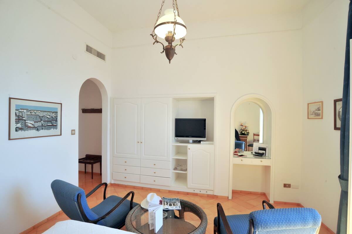 A living room with a television, white cabinets, and a chandelier.