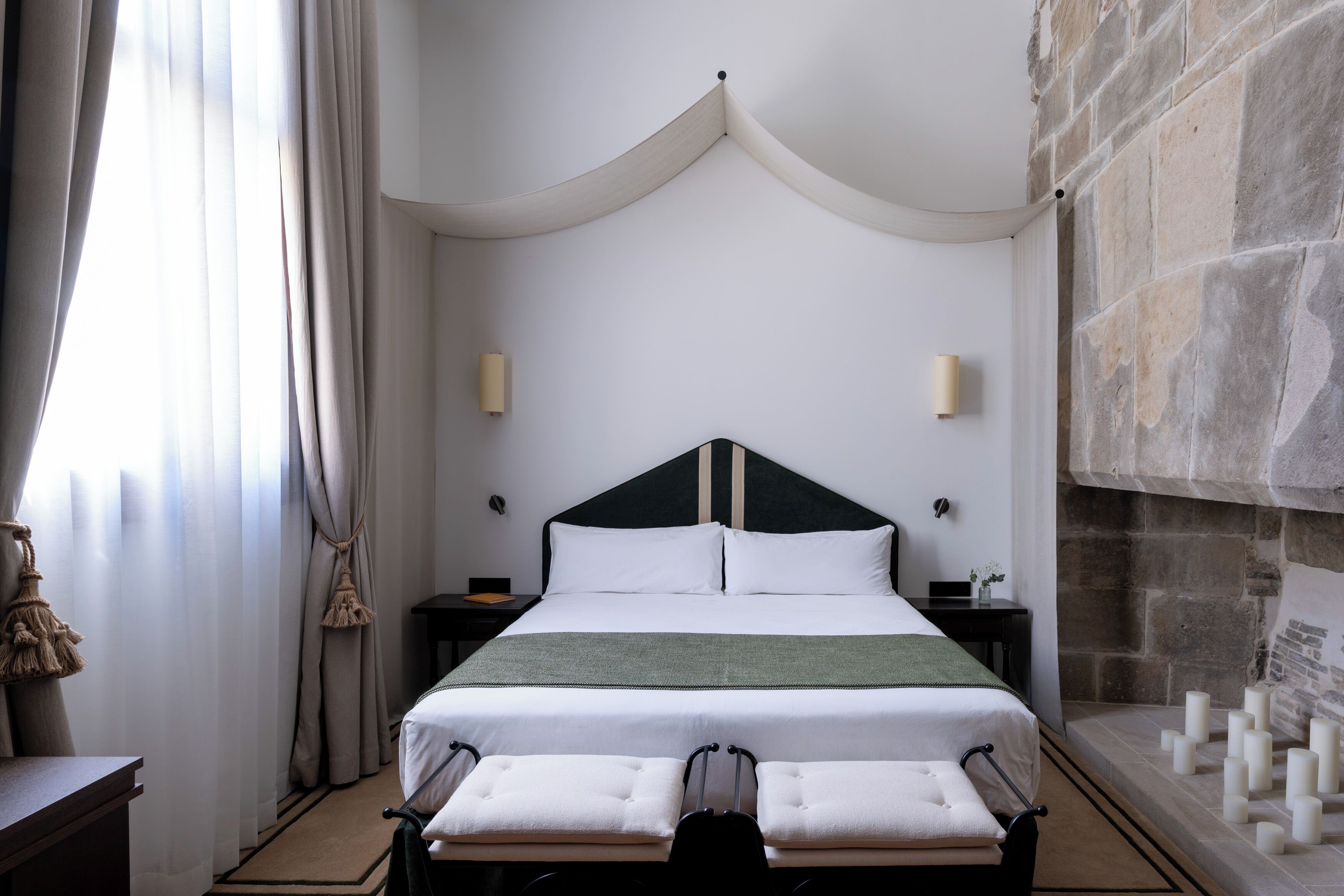 A hotel room with a large bed, a stone fireplace, and a view of the stone wall.