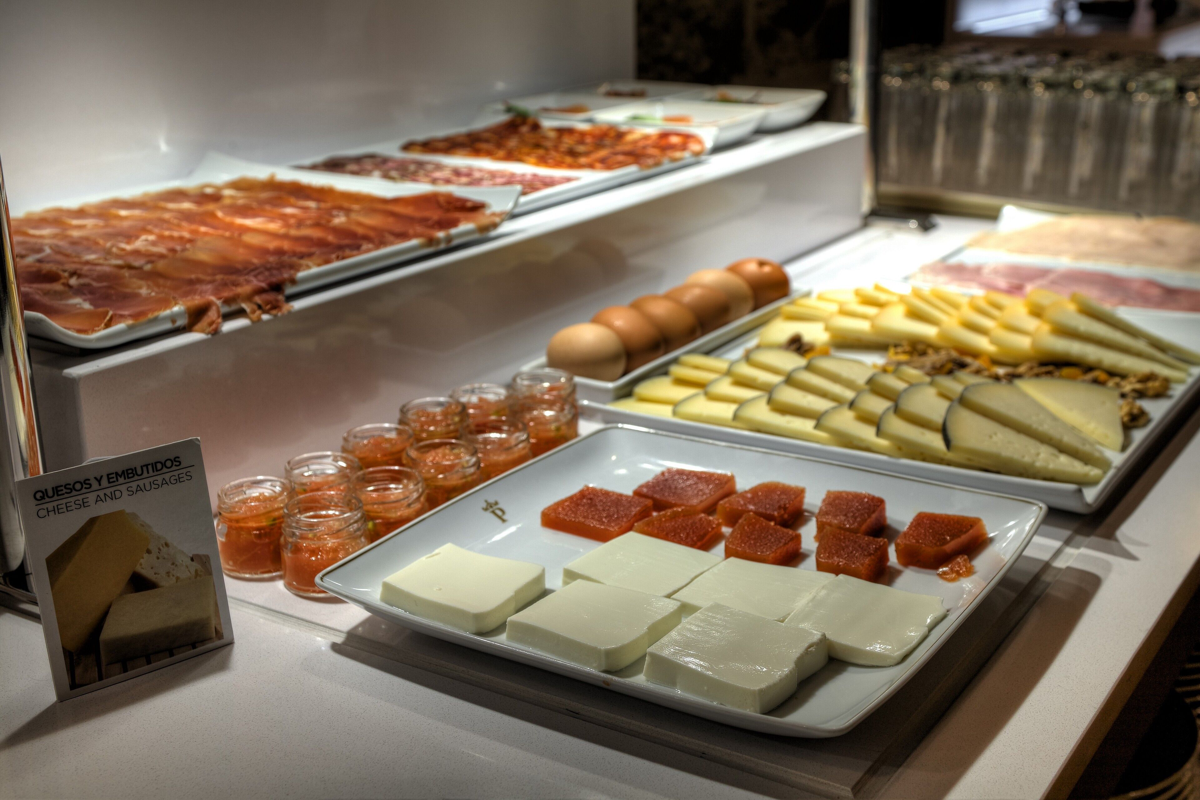 A buffet with various cheeses, meats, and fruits.