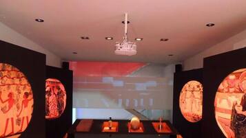 A modern interior with a projector screen, a table with candles, and wall art.