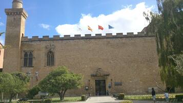 Un edificio histórico con una torre destacada, una entrada amplia y banderas en la parte superior.