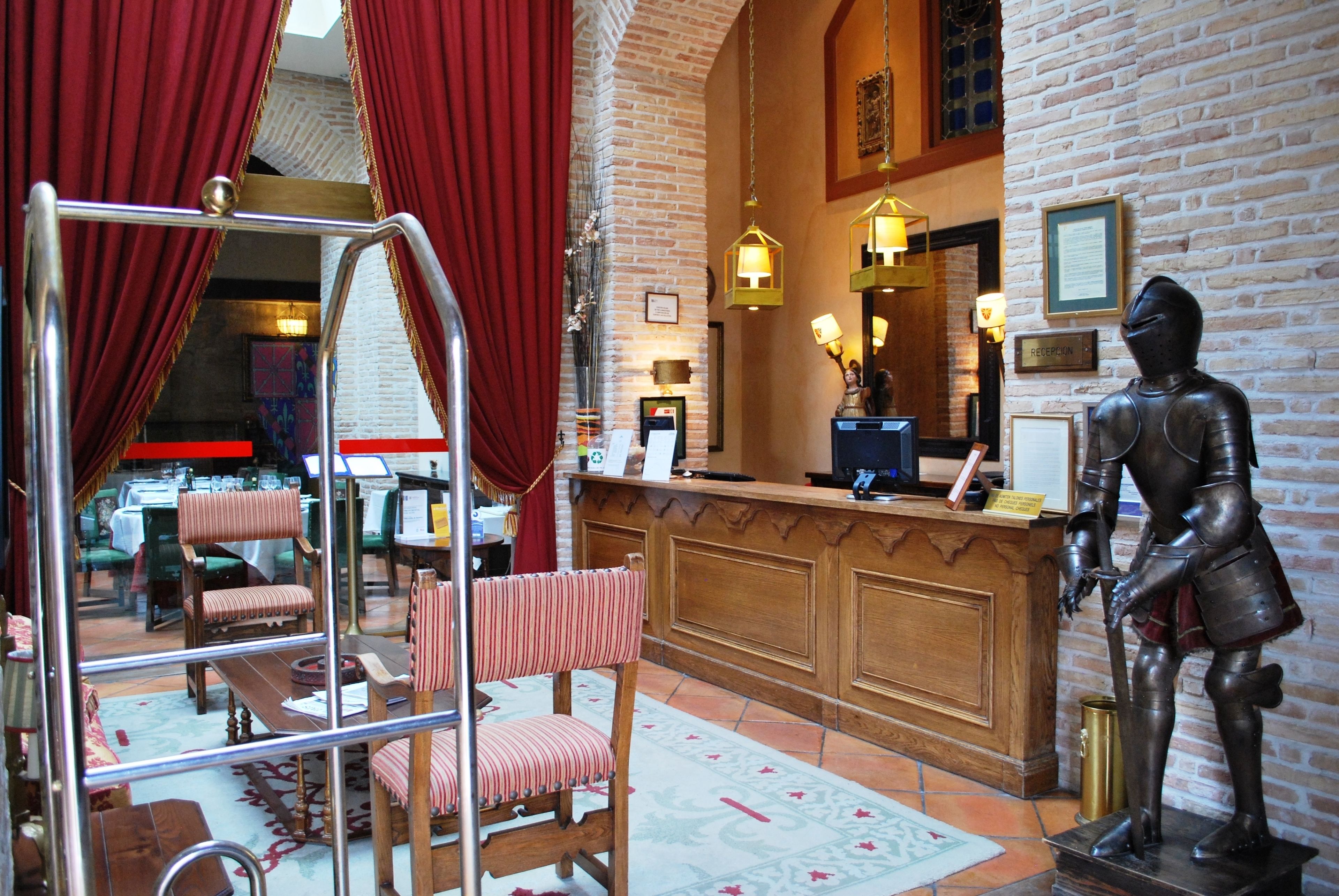 A lobby with a reception desk, a knight statue, and a mirror.
