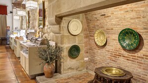 A restaurant with a brick wall, hanging plates, and a buffet area. - Parador de Olite (Olite)