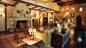 A spacious lobby with a fireplace, comfortable seating, and a chandelier. - Parador de Olite (Olite)