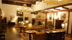 A cozy, well-lit living room with wooden furniture, a fireplace, and various decorative items. - Parador de Olite (Olite)