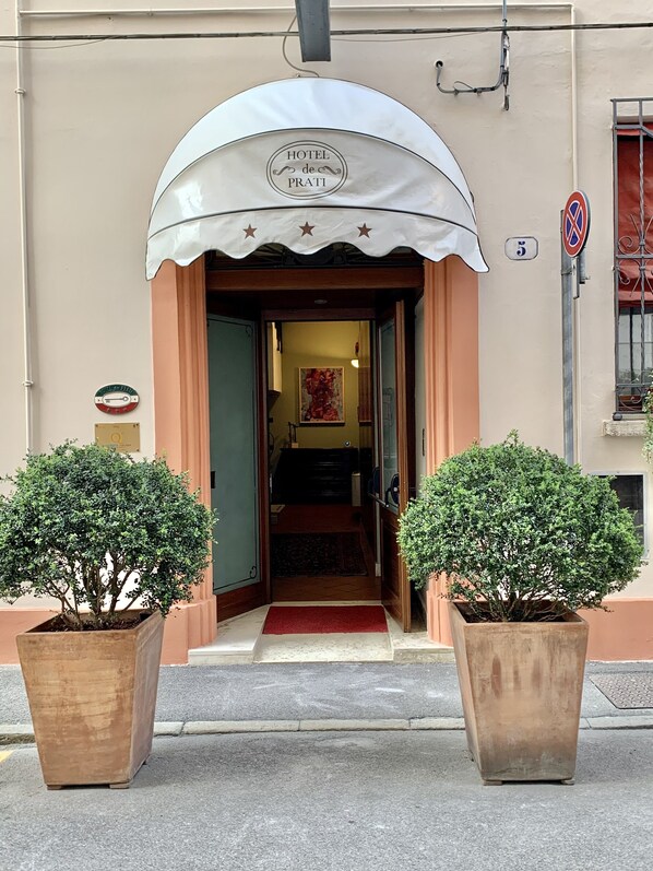 The entrance of Hotel de Prati with a classic design, including a sign above the door and a small number plaque on the wall.