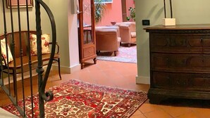 Un escalier avec une rampe, une chaise en bois avec des coussins à motifs floraux, un tapis à motifs et un meuble en bois.