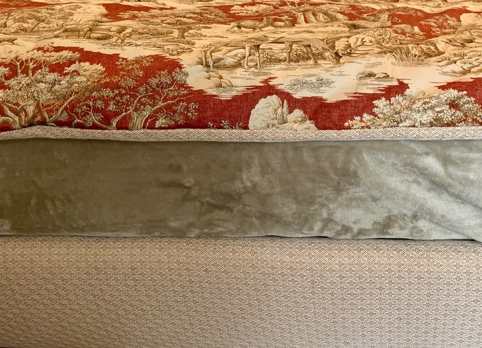 Una cama con una colcha estampada que muestra una escena de paisaje.