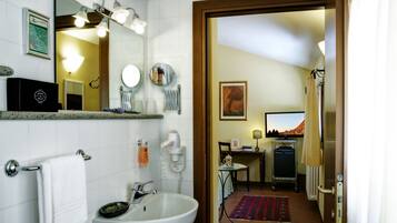 Baño de hotel con lavamanos, espejo, toallero y vista a la habitación.