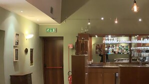 L’intérieur d’un restaurant est agrémenté de poutres en bois, de lampes suspendues, d’un bar et d’un espace repas avec des tables et des chaises.