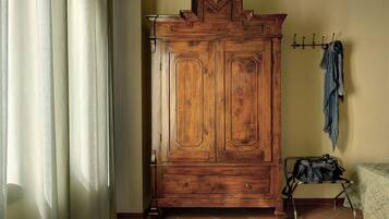 Une armoire en bois avec une porte à battants, un porte-manteau avec un manteau, et une petite table avec un sac.