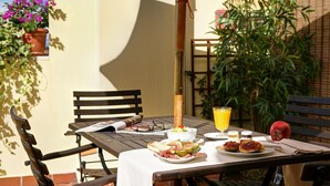 Une table dressée avec des aliments pour le petit-déjeuner, notamment des toasts, des fruits et un verre de jus d’orange, et une pomme rouge posée à côté.