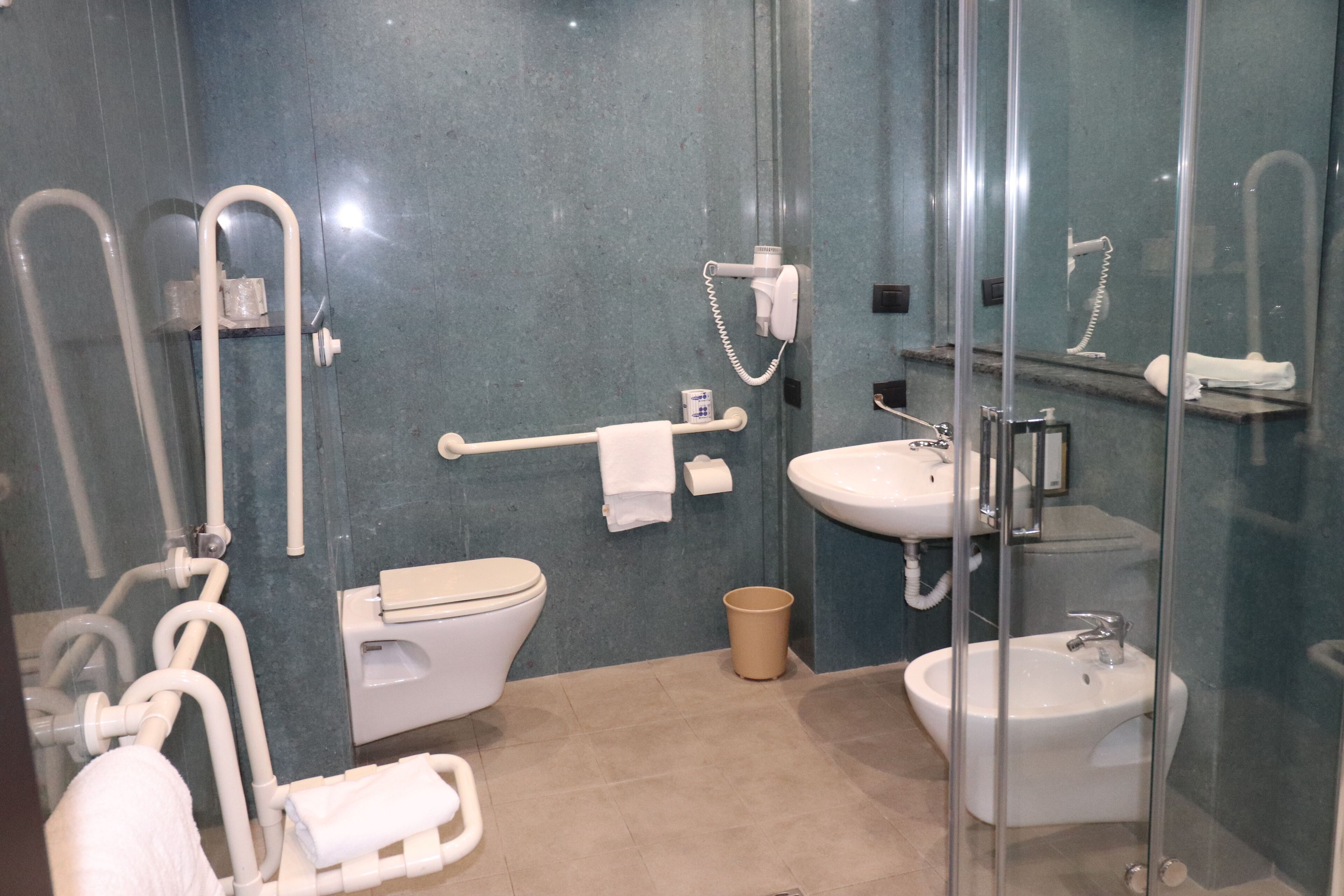 Une salle de bain moderne équipée de toilettes, d’un bidet, d’un lavabo et d’une douche à parois en verre.