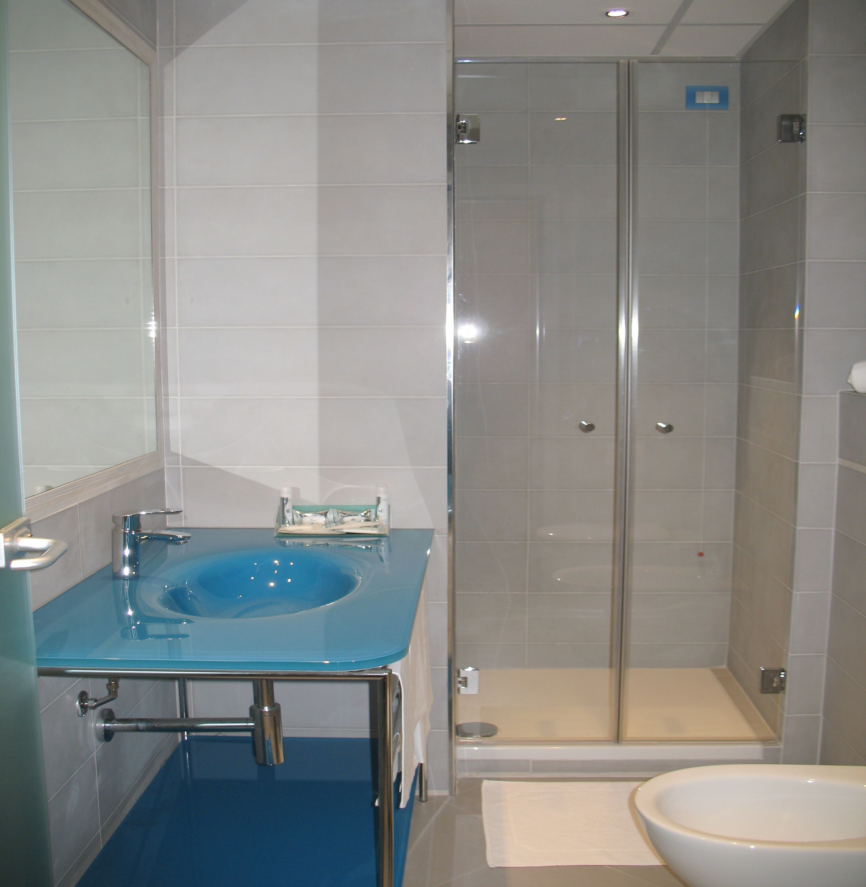 A bathroom with a blue sink, a white toilet, and a glass-enclosed shower.