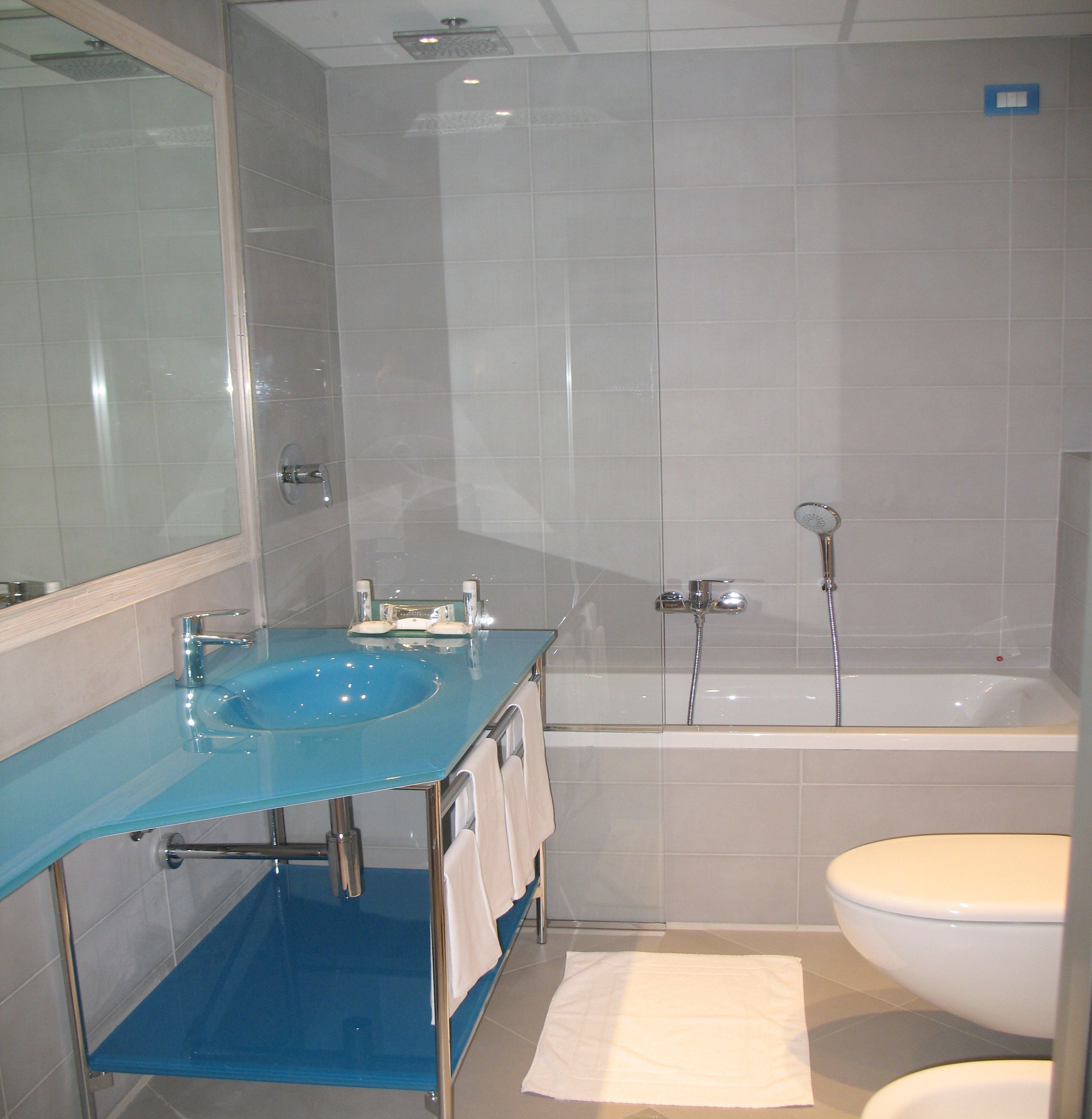 A bathroom with a blue sink, a bathtub, and a toilet.