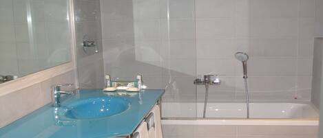 A bathroom with a blue sink, a bathtub, and a toilet.