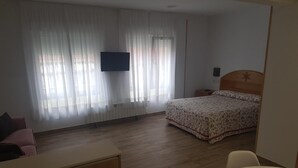 A hotel room with a bed, a desk, a chair, and a TV on the wall. - Hospedaje Magallanes (Santander)