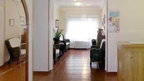 A hallway with a wooden floor, a door on the left, and a window at the end. - Hospedaje Magallanes (Santander)