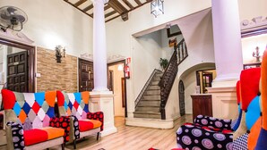 Un vestíbulo amplio con una escalera, una chimenea y sillas tapizadas de colores.
