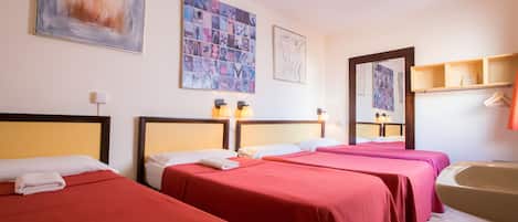 Quarto de hotel com três camas, banheira e obras de arte nas paredes.
