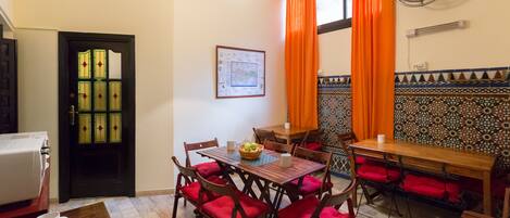 A dining area with a wooden table, red cushioned chairs, and a fan on the wall.