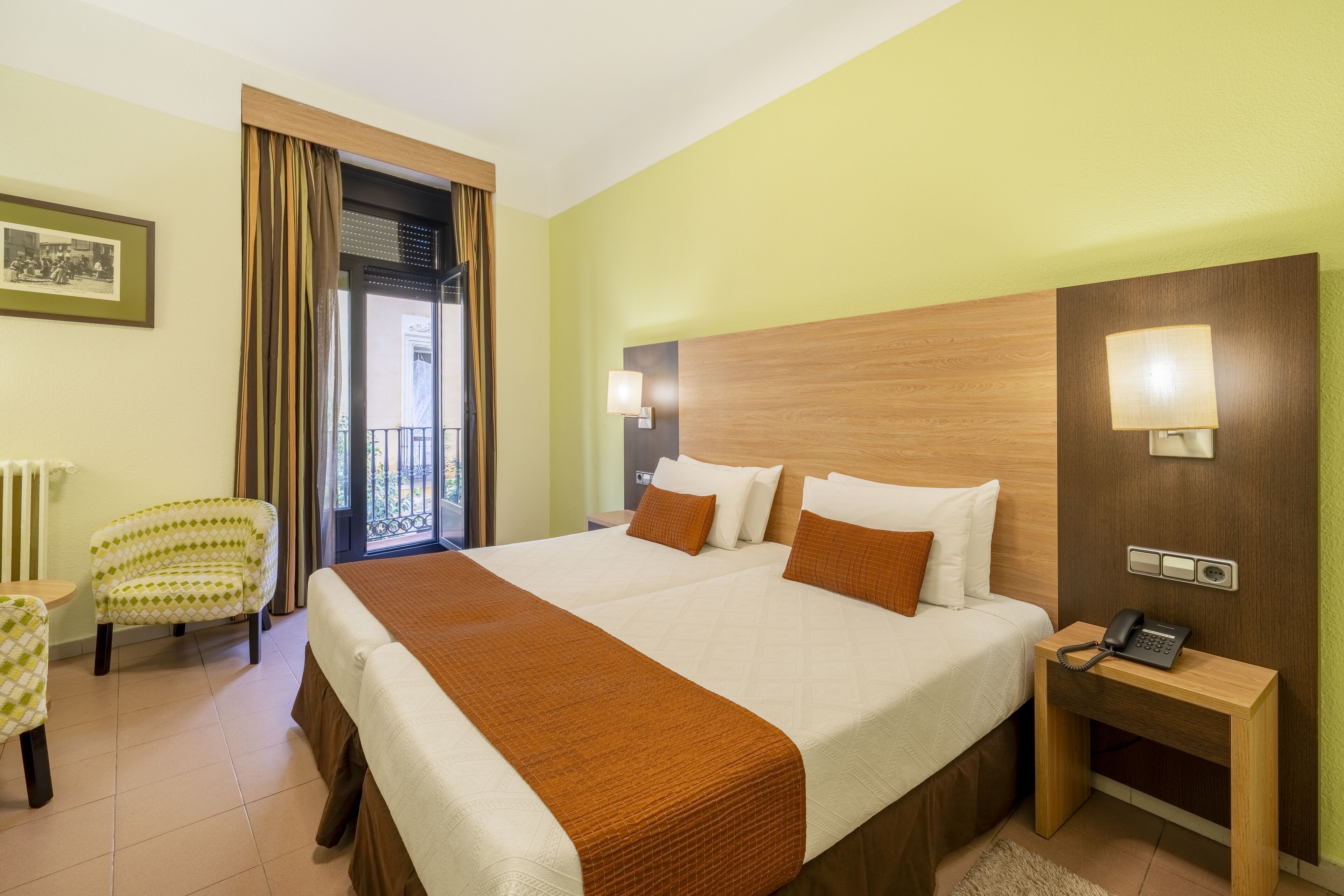 A hotel room with a large bed, two bedside tables, a chair, and a view of the outside.