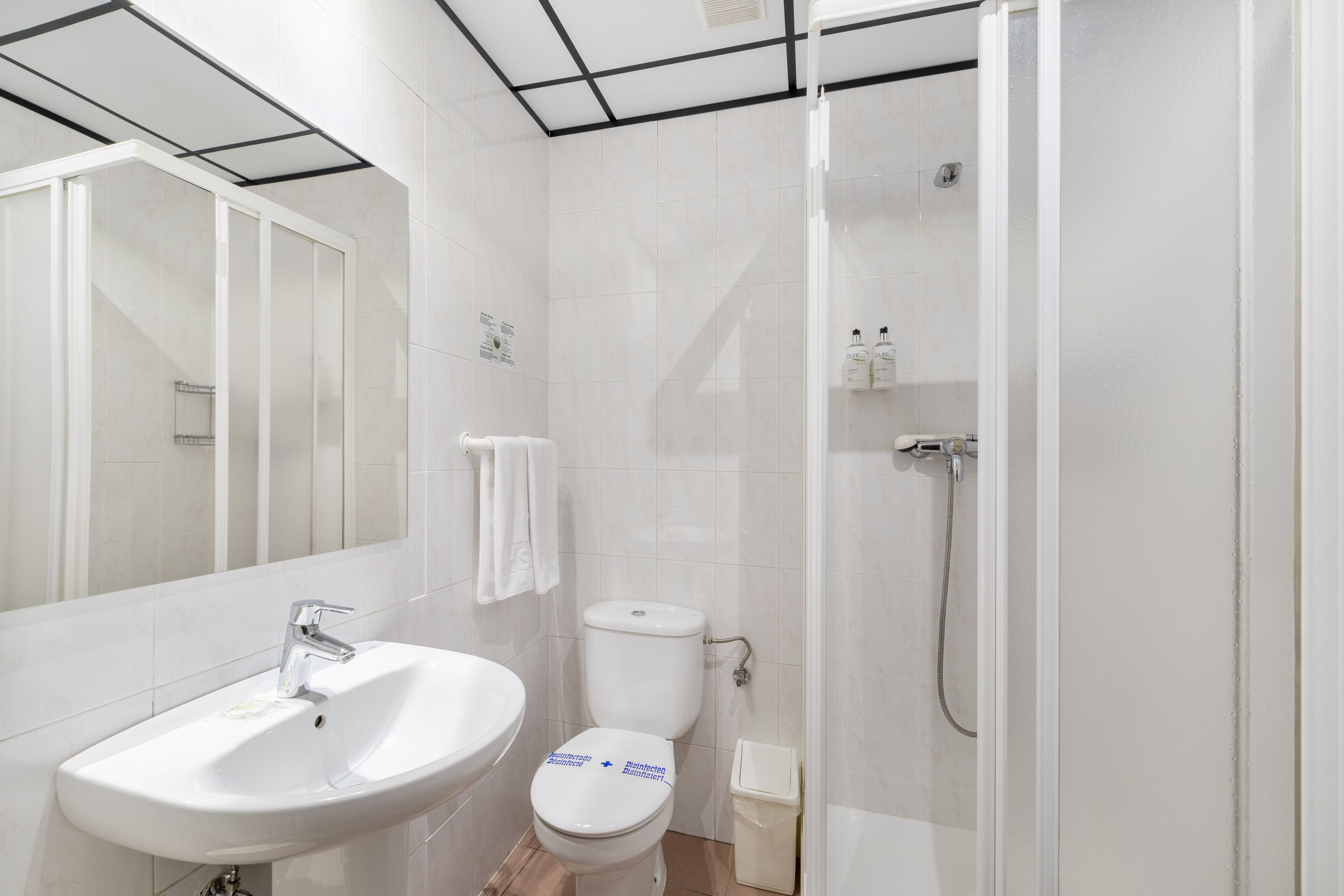 A modern bathroom with a white sink, toilet, and shower.