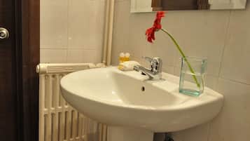 Un baño con un lavamanos blanco, un espejo encima y una puerta de madera.