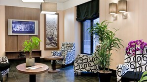 A modern lobby with a TV, seating area, and plants. - Hostal Ballesta (Madrid)