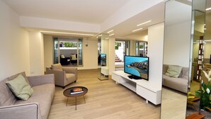 Una sala de estar moderna con televisor de pantalla plana, sofás, una mesa de centro y un espejo grande.