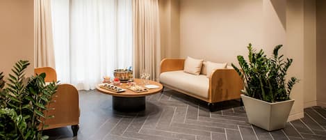 A modern living room with a sofa, coffee table, and two potted plants.