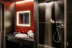 A modern bathroom with a large mirror, a sink, and a shower area.