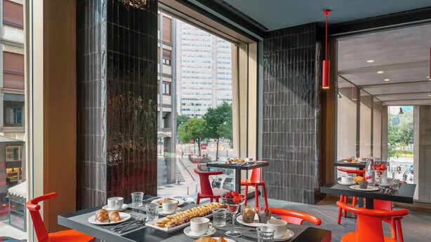 A modern dining area with a table set for breakfast, including croissants, pastries, and beverages. - Hotel Glam Milano (Milan)