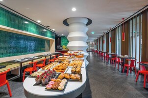 A buffet with various food items and red chairs.
