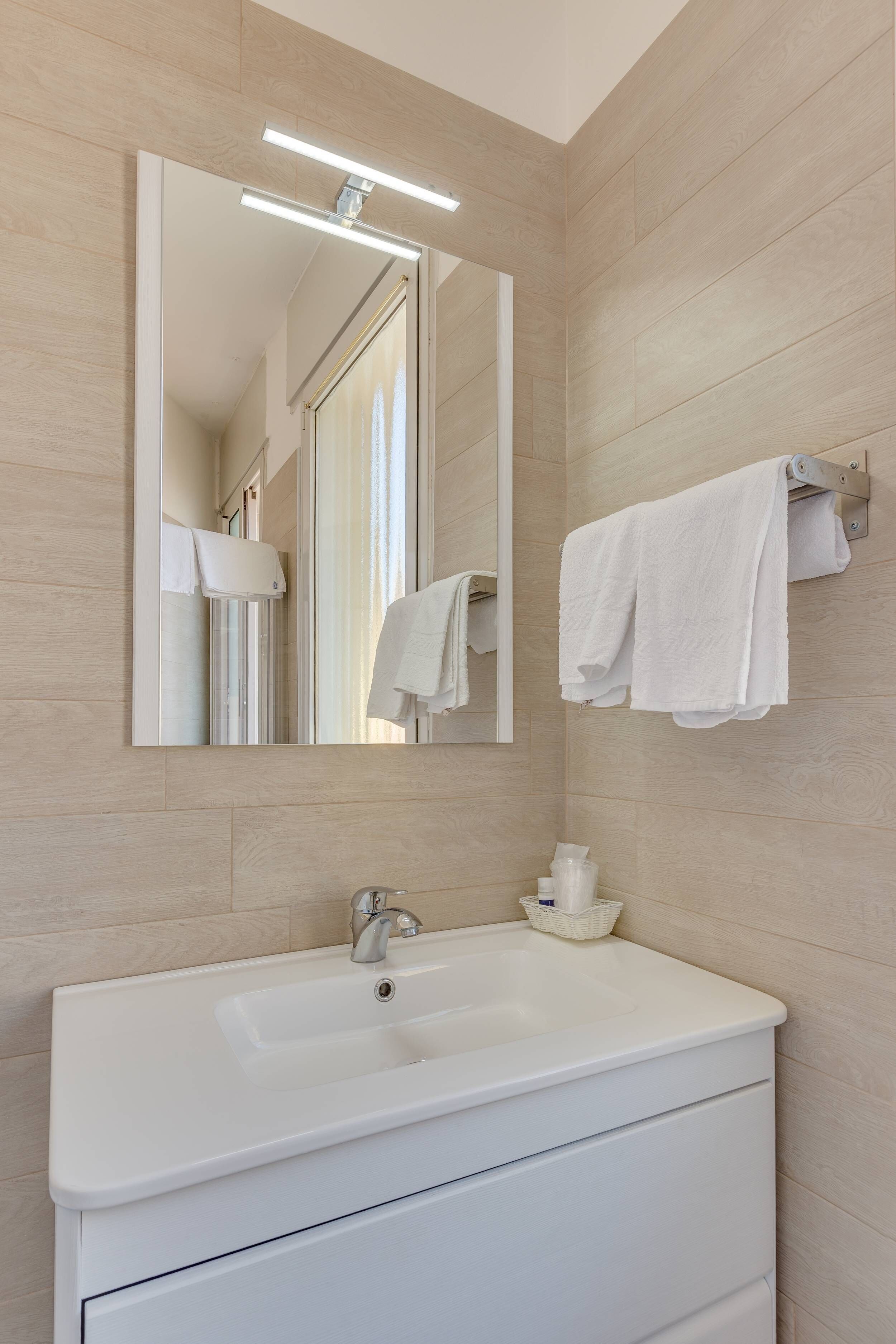 Een moderne badkamer met een wit wastafelmeubel, spiegel en handdoekhouder.