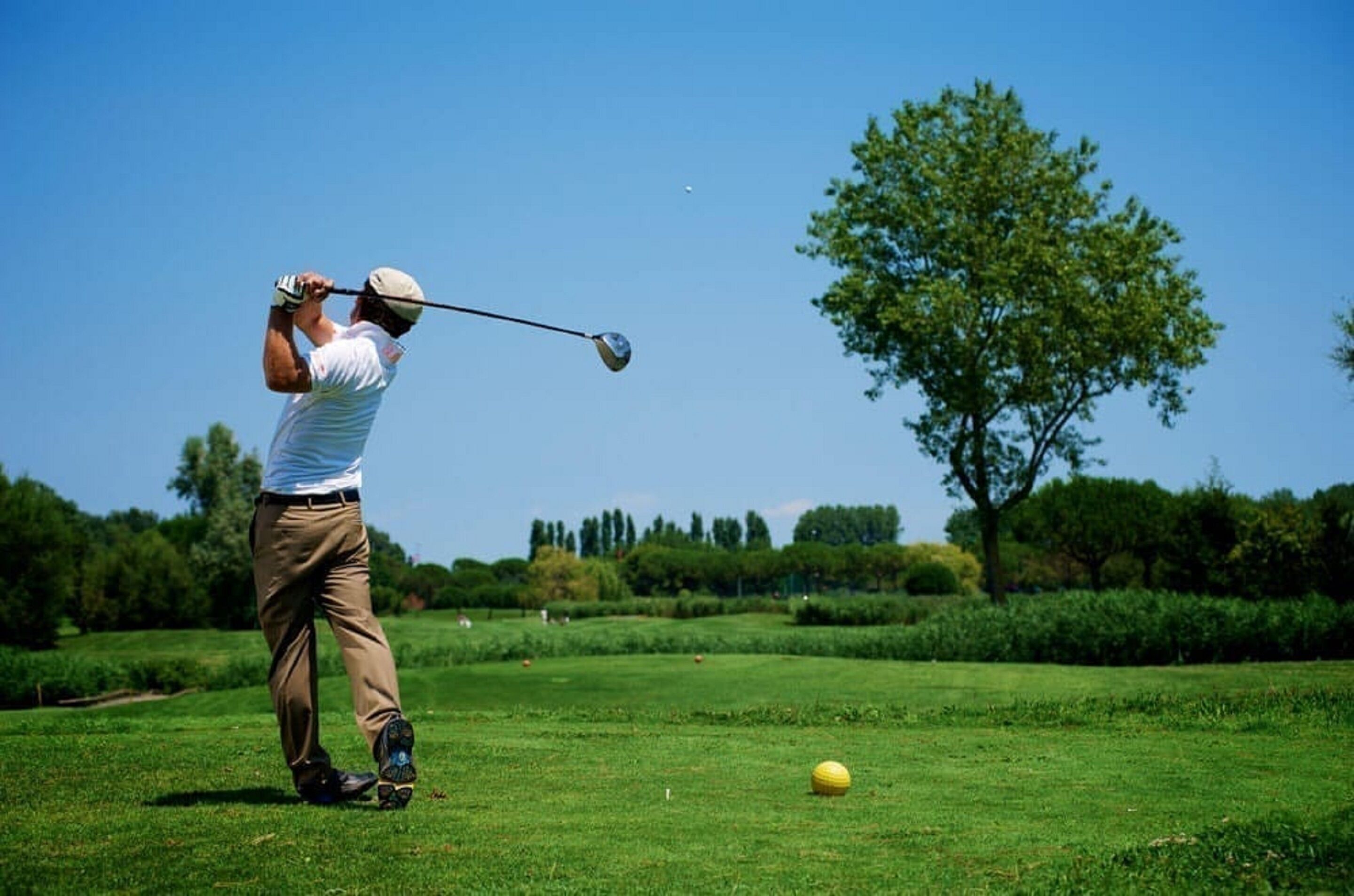Una persona jugando al golf en un día soleado.