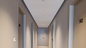 A long, narrow hallway with doors numbered 307 and 302, leading to a central door. - Valle Verde (Grammichele)