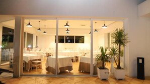 A restaurant with tables set for dining, potted plants, and hanging pendant lights. - Valle Verde (Grammichele)