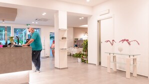 A modern reception area with a receptionist, a glass display table, and potted plants. - Valle Verde (Grammichele)
