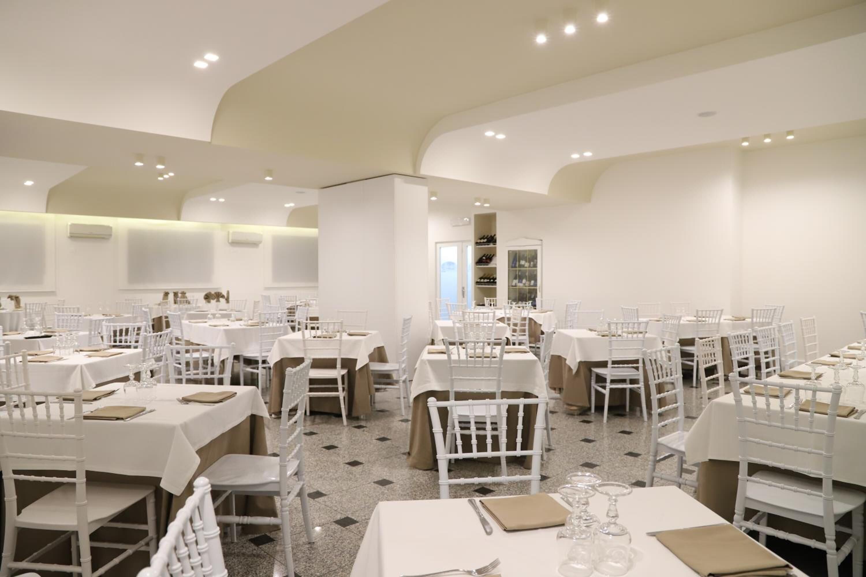 A spacious dining area with multiple tables and chairs, arranged in a modern, open layout.