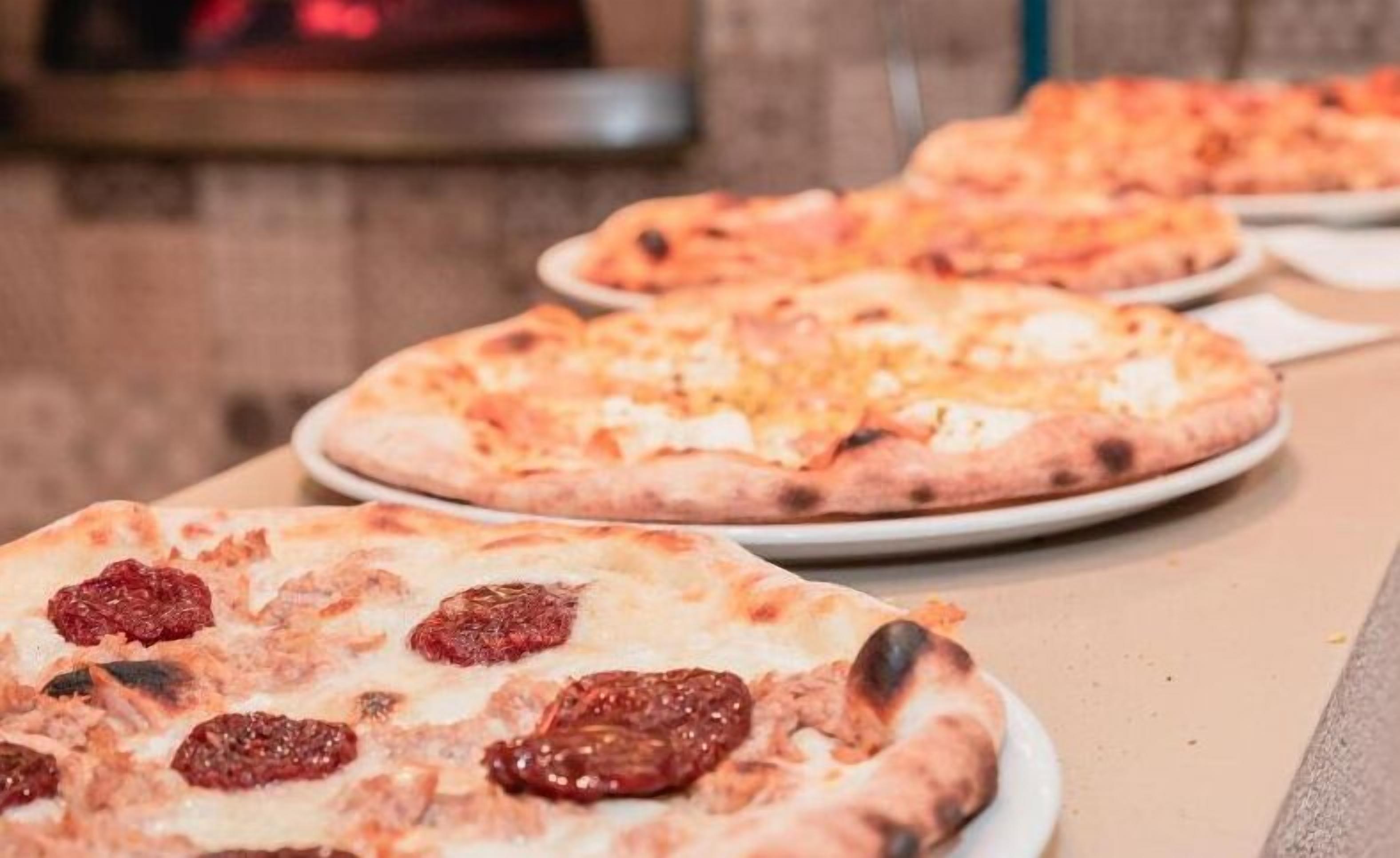 Taula amb diverses pizzes, incloent-hi una de pepperoni.