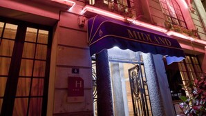 A historic building with the name "MIDLAND" illuminated in pink lights, featuring classic architecture with arched windows and a prominent entrance. - LOGIS Midland (Vichy)