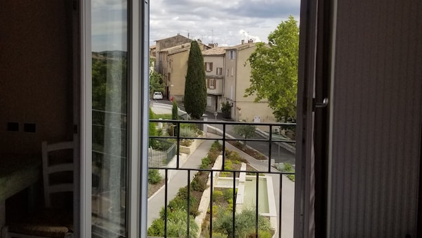 Una habitación con un amplio ventanal que da a una calle con edificios y áreas verdes.