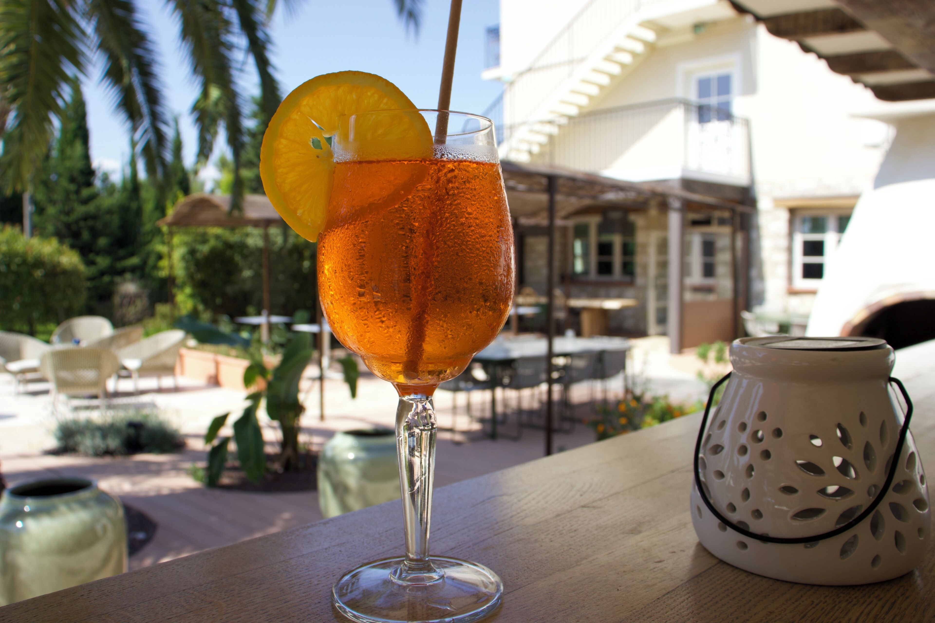 A clear glass with a beverage, garnished with an orange slice, on a wooden surface.