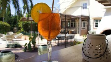 A clear glass with a beverage, garnished with an orange slice, on a wooden surface.